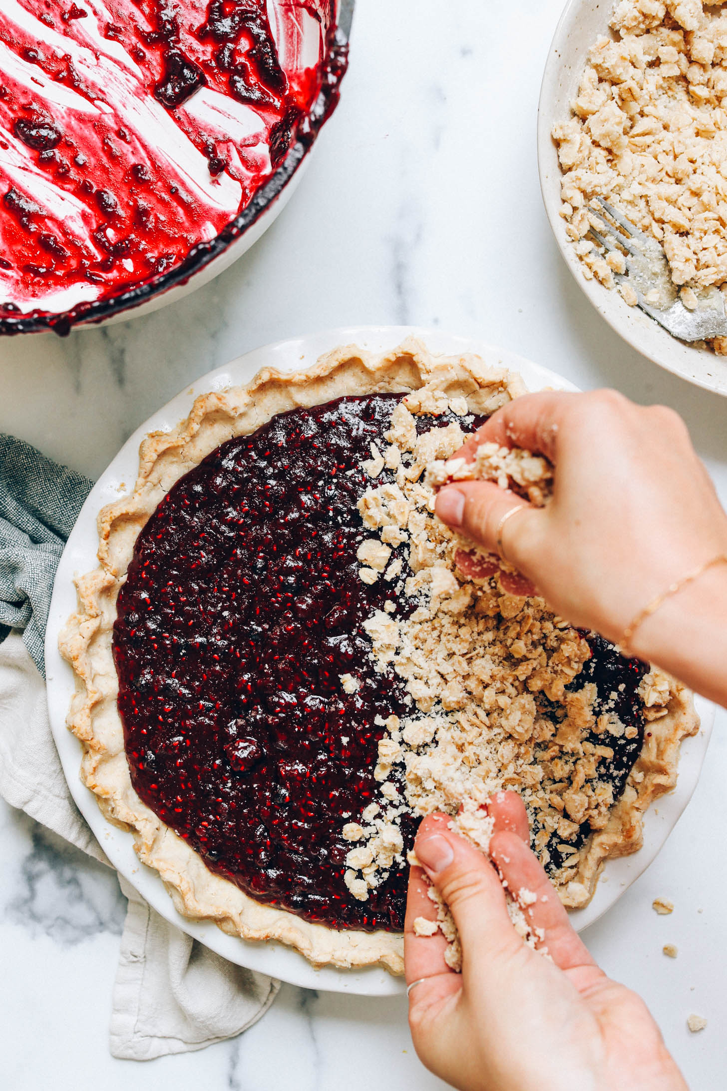 Crumbling the gluten-free pie topping onto jammy mixed berries