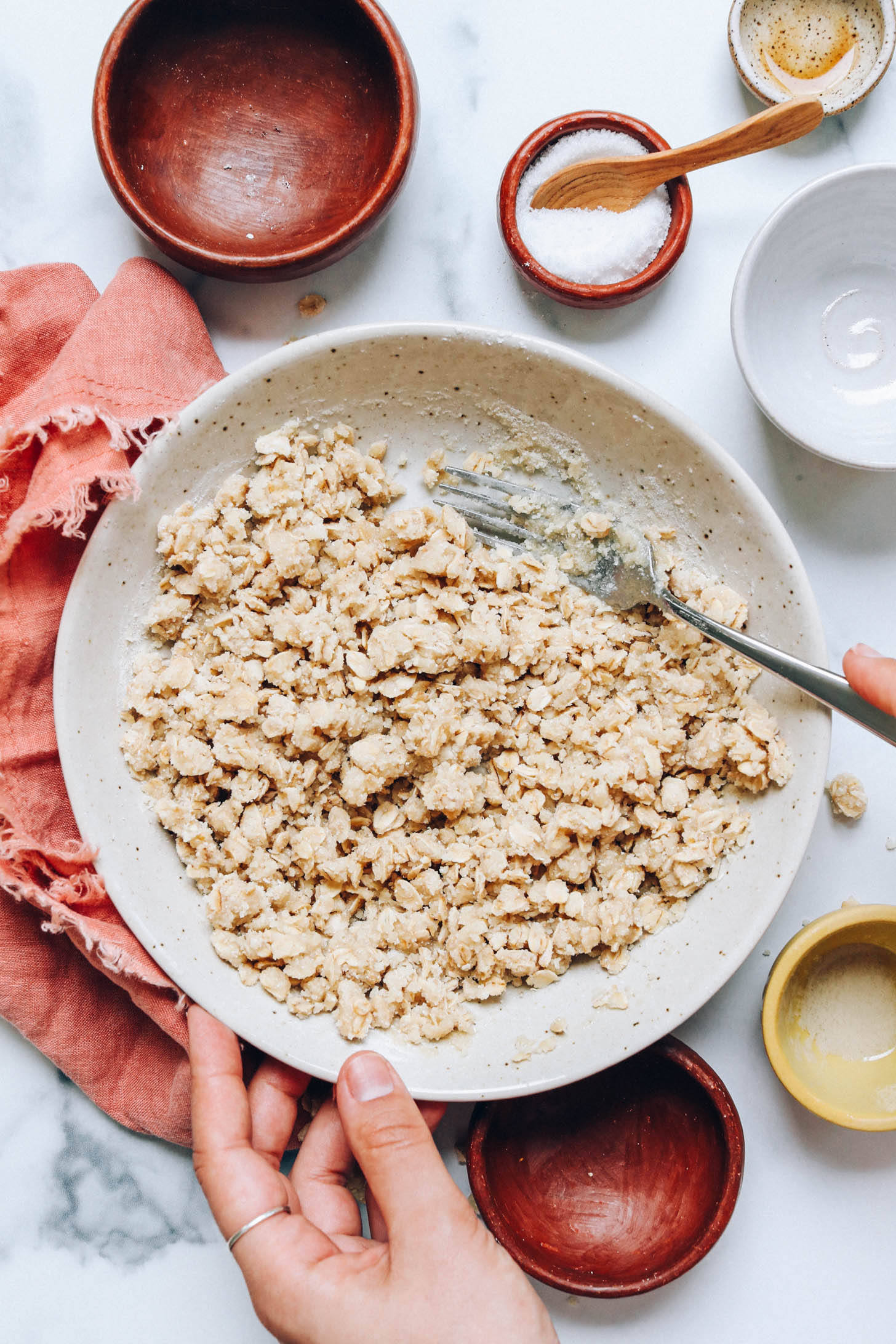 Holding a fork in a bowl of gluten-free crumble topping