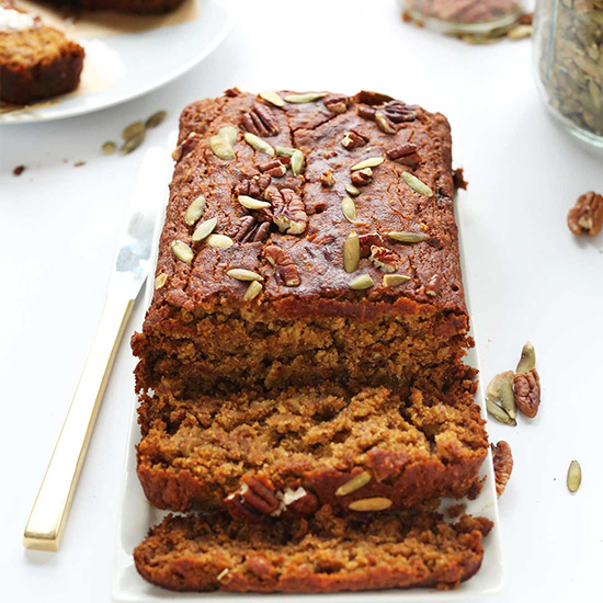 Partially sliced loaf of Vegan GF Pumpkin Bread on a tray