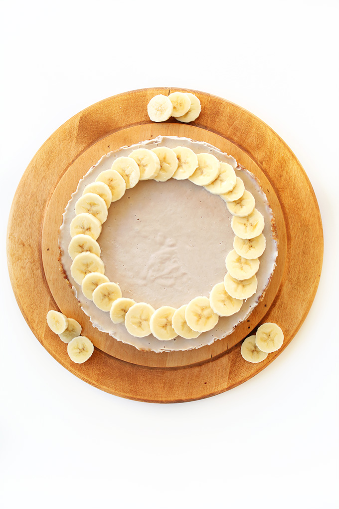 Cutting board with Vegan Banana Cheesecake surrounded by banana slices