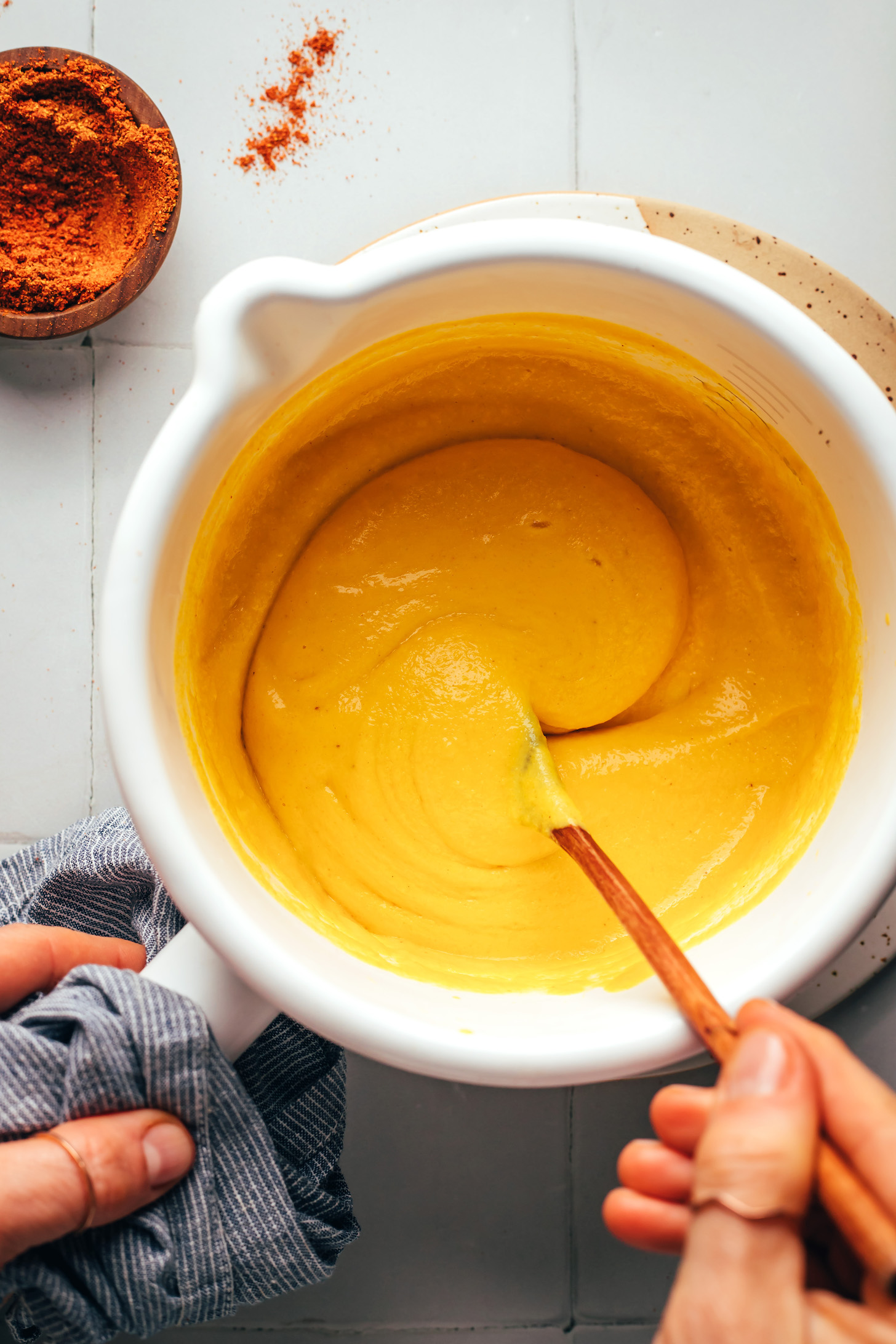 Stirring vegan cheddar cheese in a saucepan