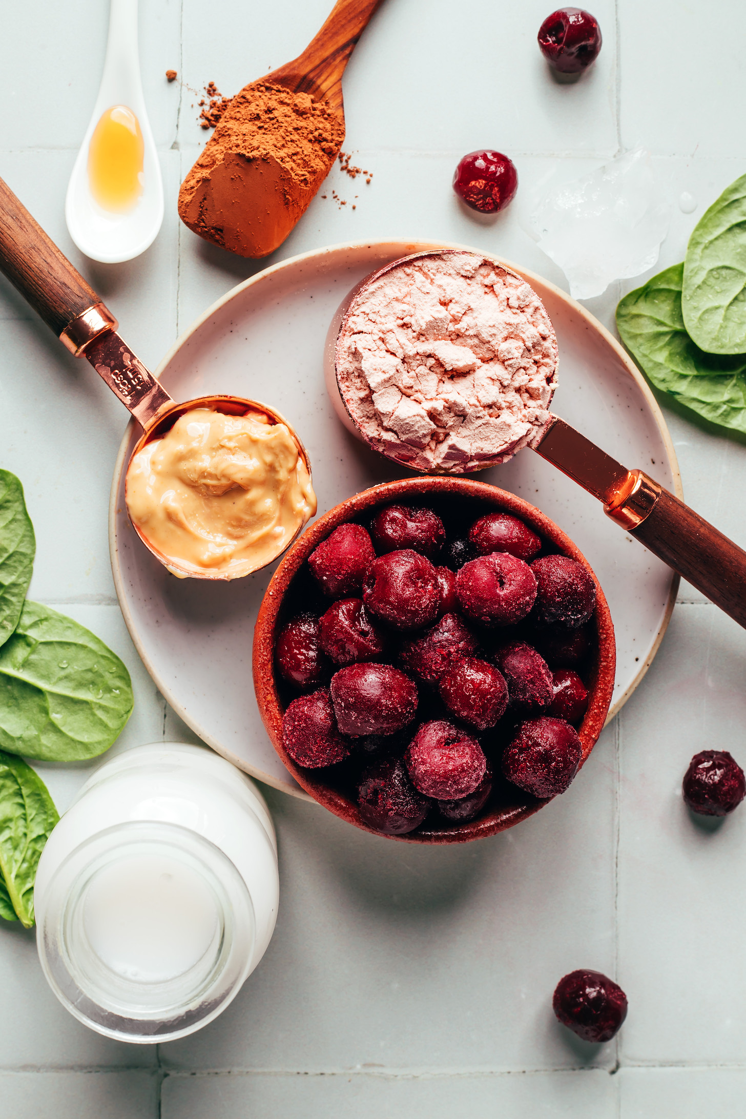 Maple syrup, cocoa powder, protein powder, frozen cherries, cashew butter, almond milk, and baby spinach