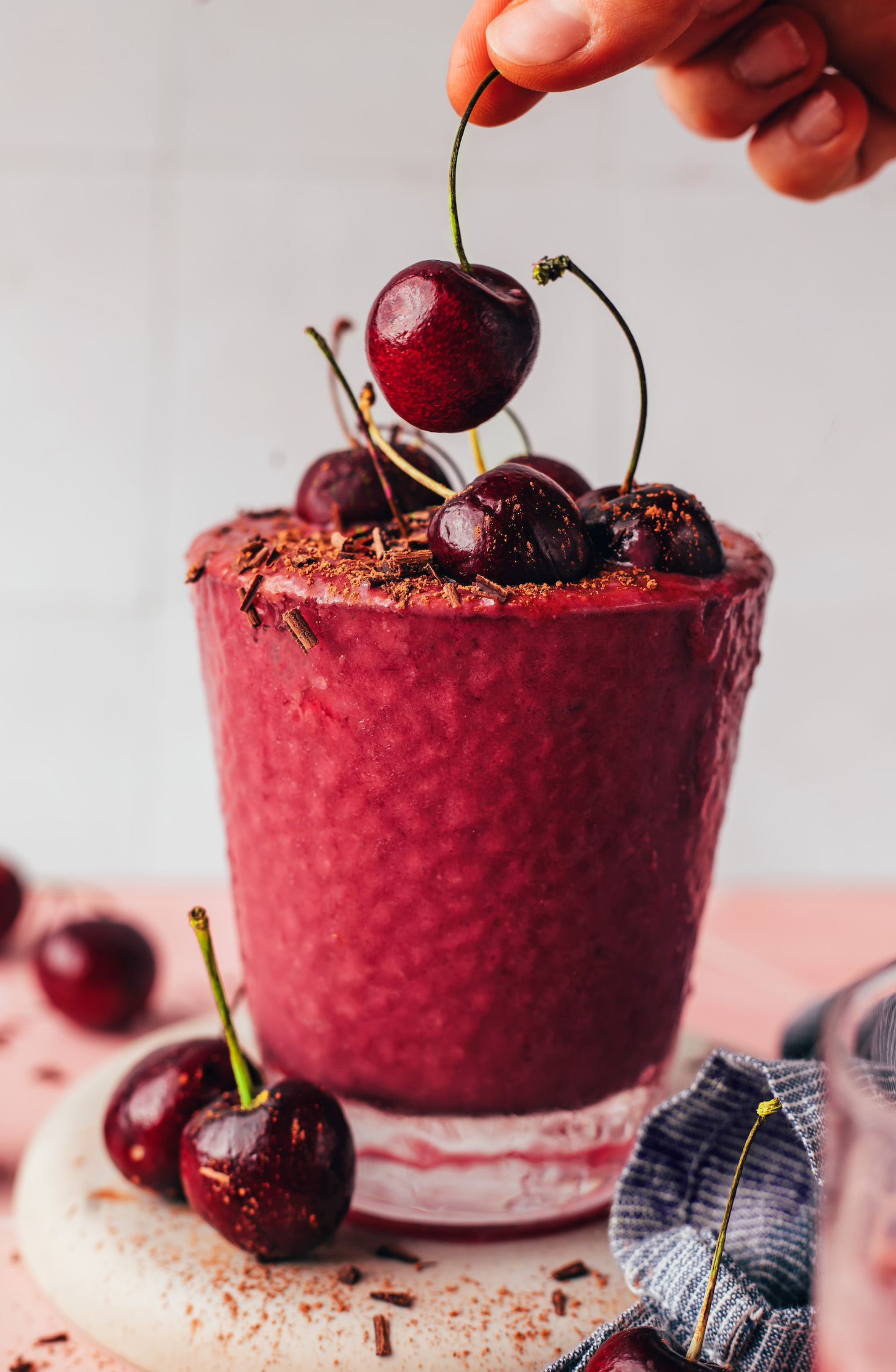 Placing a cherry on top of a glass filled with our chocolate cherry protein shake recipe