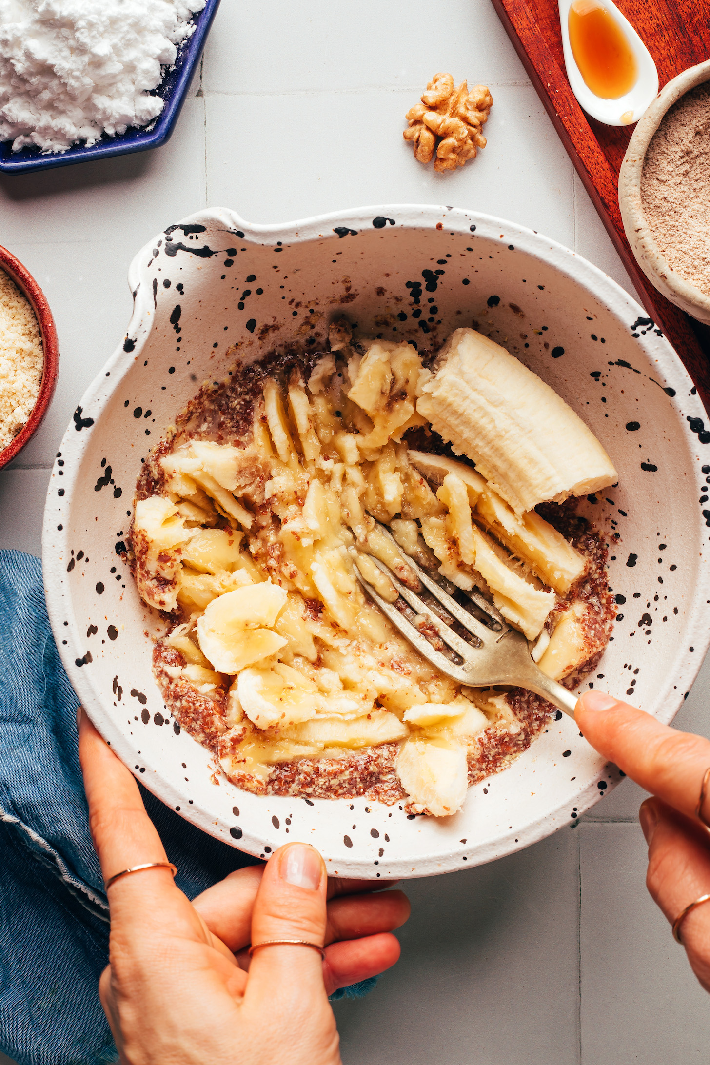 Using a fork to mash a banana in a bowl with flax egg