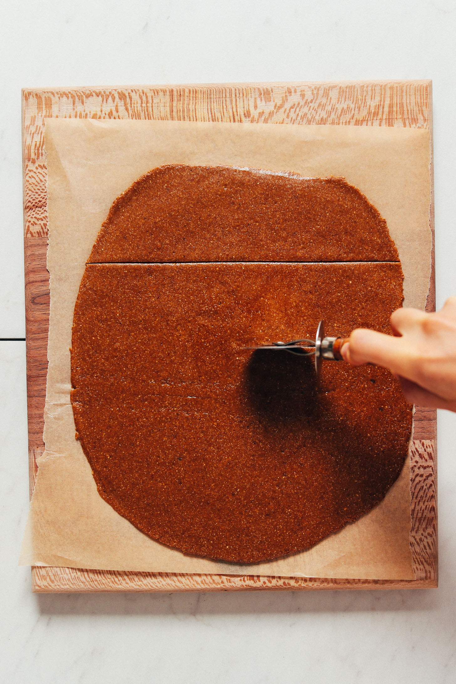 Using a pizza cutter to cut dough into graham cracker shapes