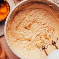 Using an electric mixer to mix a fluffy vegan pumpkin spice frosting