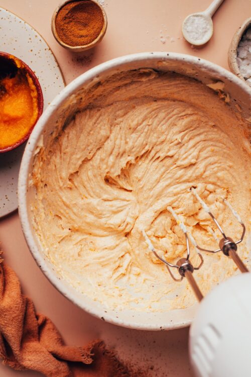 Using an electric mixer to mix a fluffy vegan pumpkin spice frosting