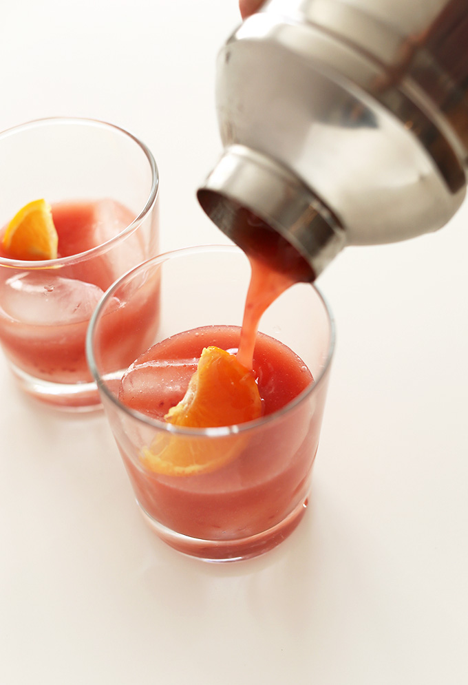 Pouring Winter Bourbon Smash from a shaker into two glasses