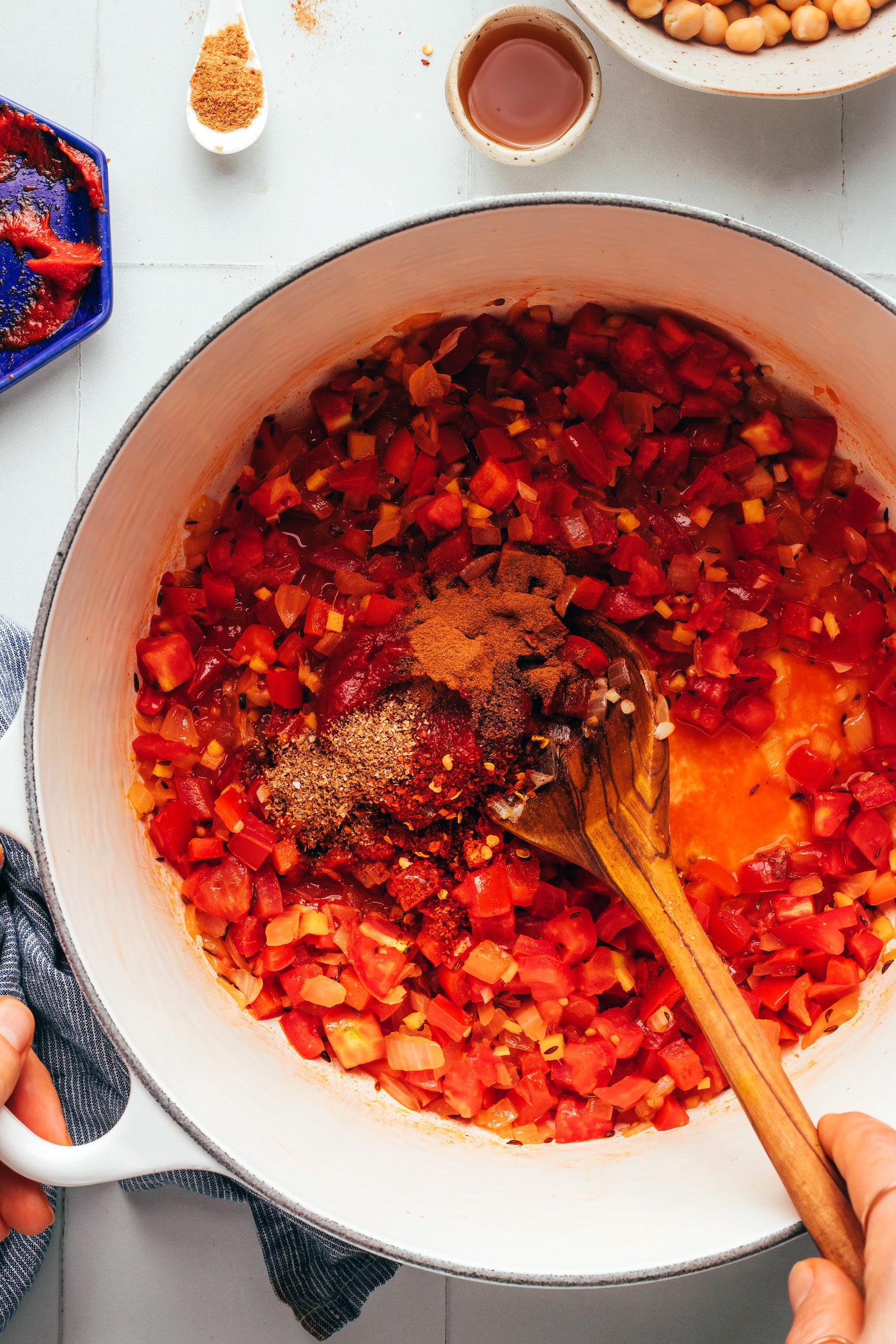 Spices, tomato paste, fresh tomatoes, and sautéed veggies in a pot