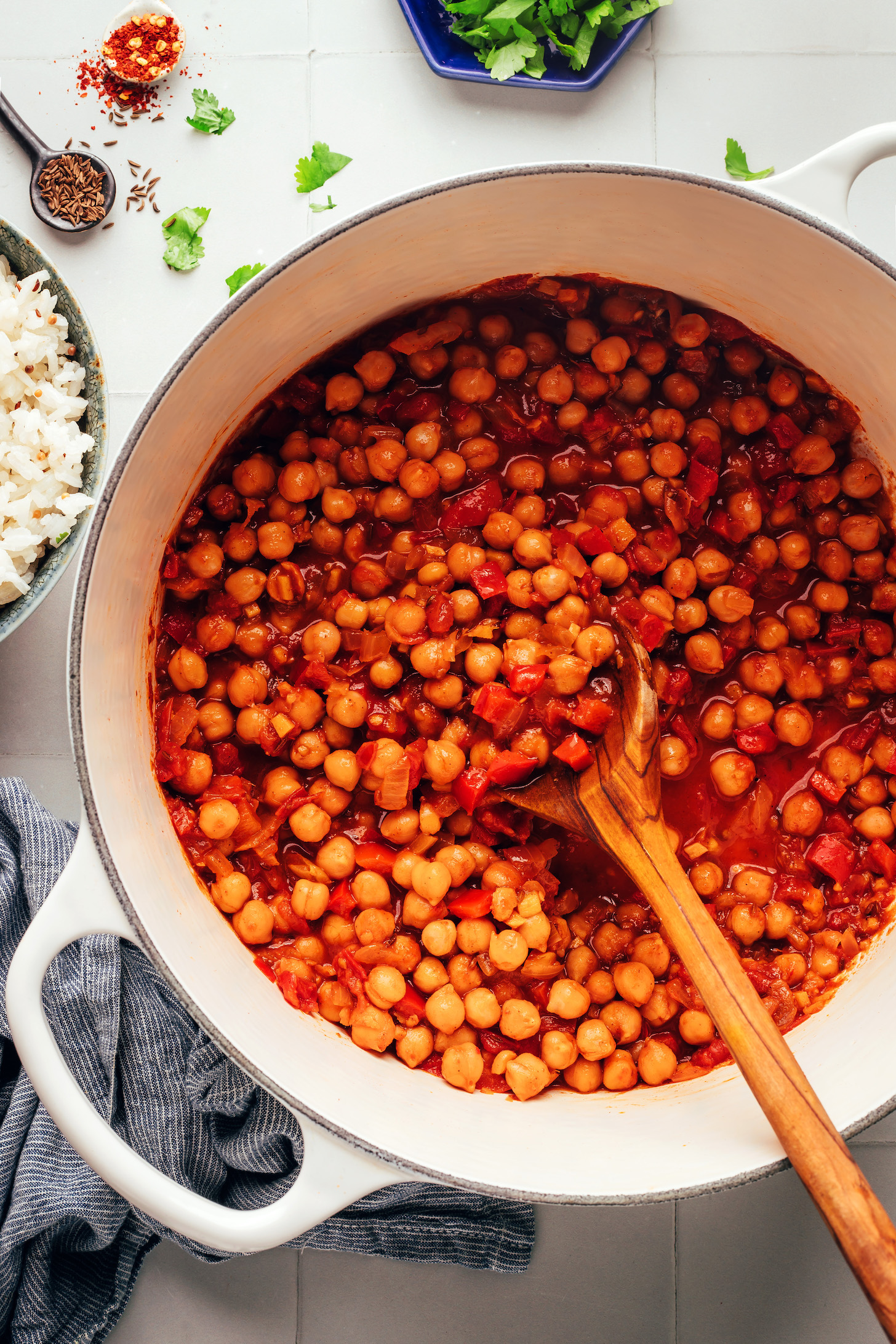 Using a wooden spoon to stir a pot of our warming 1-pot vegan chickpea curry inspired by vindaloo